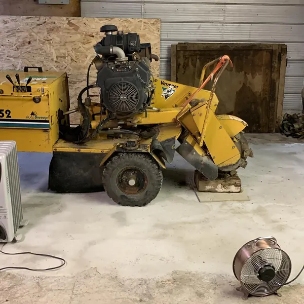 A yellow stump grinder parked in a shop.